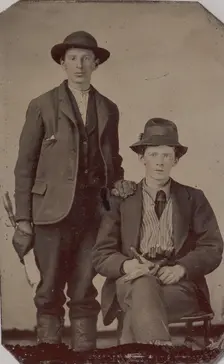 Two Young Men, One Seated and One Standing, Holding Carpentry Tools, 1870s-90s. Creator: Unknown