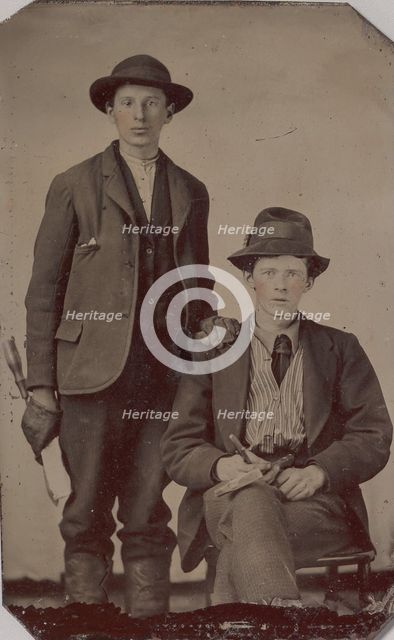 Two Young Men, One Seated and One Standing, Holding Carpentry Tools, 1870s-90s. Creator: Unknown.