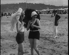 Two Young Female Civilians Wearing Swimsuits Holding Feathered Parasols on a Beach, 1920. Creator: British Pathe Ltd