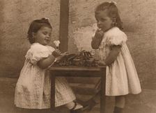 Two young girls by a table 1937