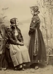 Two young girls pose in costumes from Dala-Floda with floral jackets and hats, 1890-1900. Creator: Helene Edlund