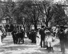 U.S. Naval Academy, Annapolis: 4 midshipmen carrying a man; crowd of guests along sidewalk, (1902?). Creator: Frances Benjamin Johnston
