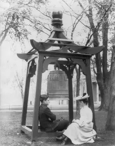 U.S. Naval Academy, Annapolis, Md. 1902?: midshipman and girl sitting beneath bell, (1902?). Creator: Frances Benjamin Johnston
