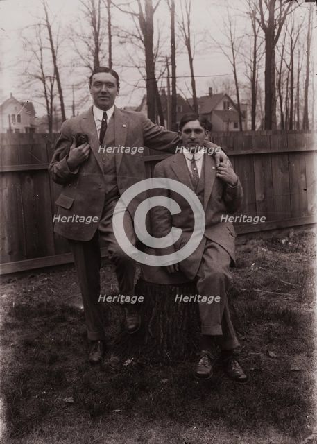 Untitled (two men holding small dog; one sitting on a stump, Fisher St., backyard), c1915. Creator: Wendell Hotter.
