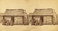 Uncle Ben's cabin, [Elderly couple sitting in front of a cabin], (1868-1900?). Creator: Unknown