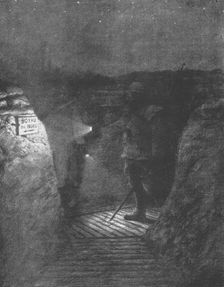 'Une tournee d'inspectionnocturne dans les boyaux, a la lueur discrete des lampes de poche. 1916. Creator: Unknown