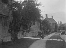 Unidentified 4-seater tourer in a village, c1920s. Artist: Bill Brunell