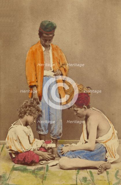 Unidentified man with basket standing, plus two boys seated playing cards, 1865-1870. Creator: Giorgio Conrad.