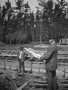 Unidentified man at a construction site studying building plans, between 1896 and 1942. Creator: Arnold Genthe