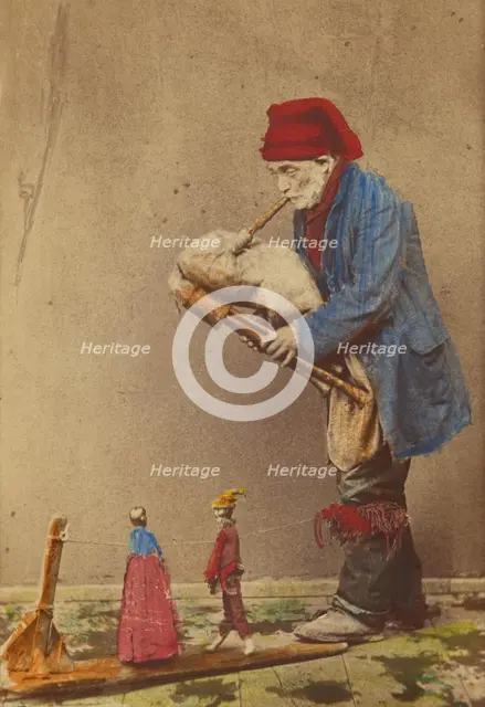 Unidentified man in cap playing a bagpipe-type instrument with two marionettes, about 1870. Creator: Giorgio Conrad.