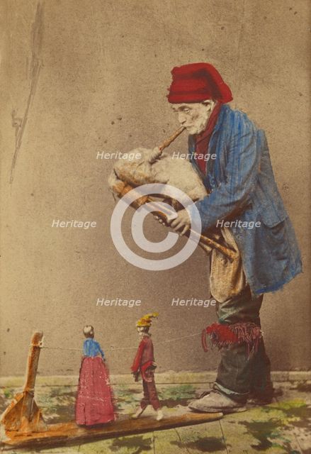 Unidentified man in cap playing a bagpipe-type instrument with two marionettes, about 1870. Creator: Giorgio Conrad.