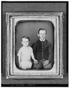Unidentified boy seated in chair with child standing to left, three-quarter..., between 1850 & 1860. Creator: Unknown