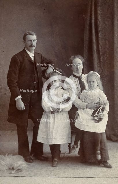 Unidentified family with two girls holding dolls. Creator: Priyalalls Photography.