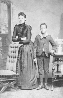 Unidentified standing figures: woman, her folded arms leaning on back of chair..., c1890. Creator: J. N. Wilson
