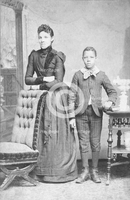 Unidentified standing figures: woman, her folded arms leaning on back of chair..., c1890. Creator: J. N. Wilson.