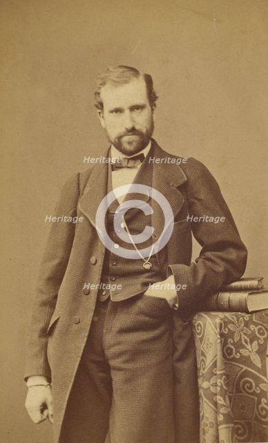 Unidentified well-dressed bearded man standing, elbow on books on a table, 1865-1870. Creator: Bayard & Bertall.