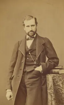 Unidentified well-dressed bearded man standing, elbow on books on a table, 1865-1870. Creator: Bayard & Bertall