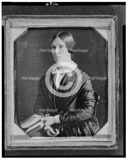 Unidentified woman, half-length portrait, facing left, seated holding book, between 1846 and 1856. Creator: Marcus Aurelius Root.