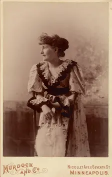 Unidentified woman in profile, leaning on a chair, holding a feather fan, about 1890. Creator: Murdock and Company