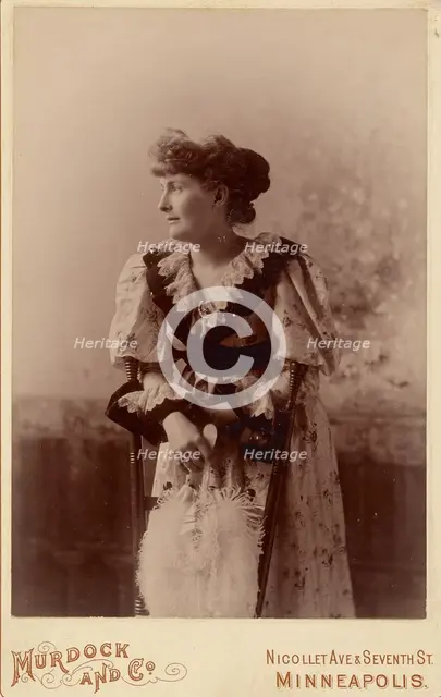 Unidentified woman in profile, leaning on a chair, holding a feather fan, about 1890. Creator: Murdock and Company.