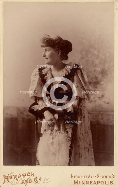 Unidentified woman in profile, leaning on a chair, holding a feather fan, about 1890. Creator: Murdock and Company.