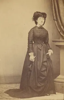 Unidentified woman wearing a hat and long dark dress, about 1868. Creator: Mathew Brady