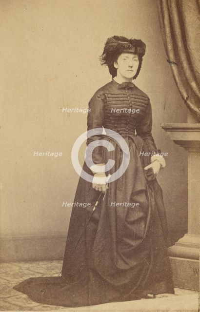 Unidentified woman wearing a hat and long dark dress, about 1868. Creator: Mathew Brady.