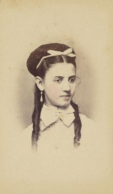 Unidentified young woman with two long curls, wearing a white bow in hair, 1870-1875. Creator: C.L. Lochman