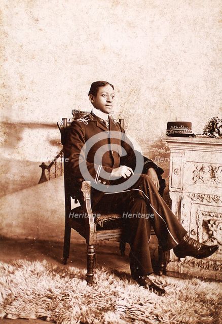 Uniformed man seated, on the mantlepiece is his cap, embroidered with the name...., c1900-c1909. Creator: Roche.