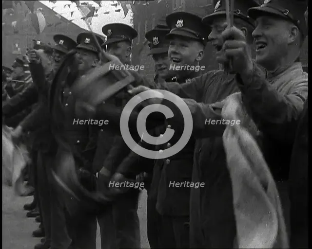 Uniformed British Soldiers Cheering and Smiling Whilst Waving Flags, 1937. Creator: British Pathe Ltd.