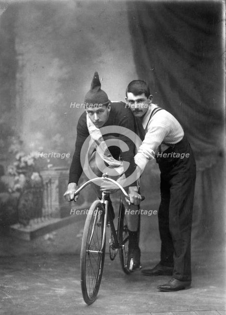 Unknown man on a  bicycle, studio portrait (Championship of Queensland sash/ribbon), 1905. Creator: Robert Augustus Henry L'Estrange.