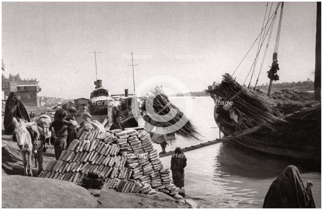 Unloading cargo from a boat, Muhaila, Baghdad, Iraq, 1925.Artist: A Kerim