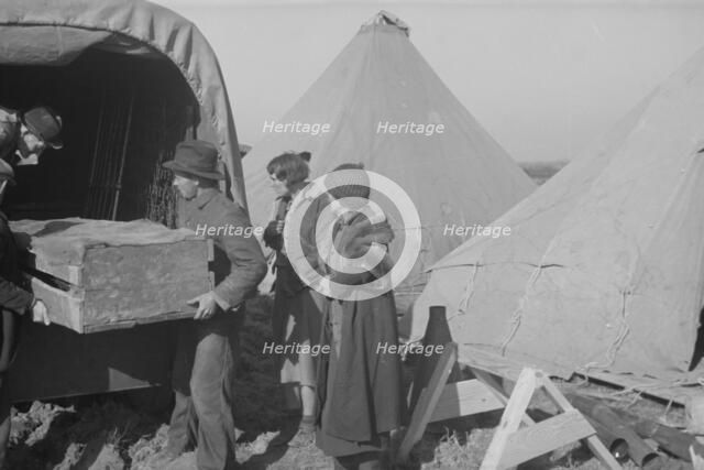 Unloading household goods of a family of white flood refugees in camp, Forrest City, Arkansas, 1937. Creator: Walker Evans.