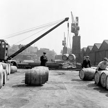 Unloading wine barrels, London Docks, 1953. Creator: Henry Grant