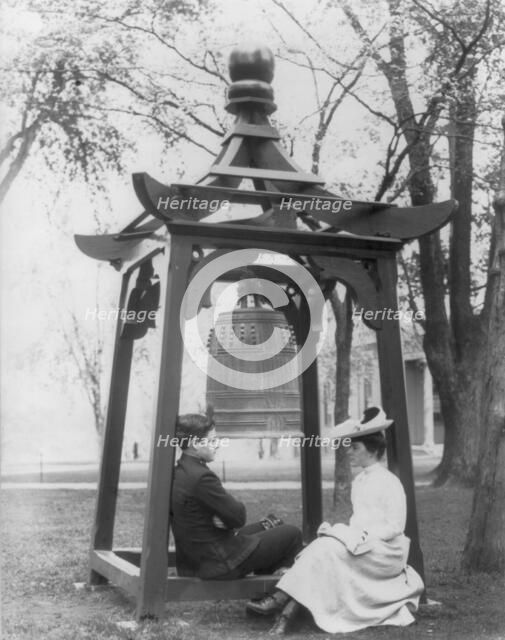 U.S. Naval Academy, Annapolis, Md. 1902?: midshipman and girl sitting beneath bell, (1902?). Creator: Frances Benjamin Johnston.