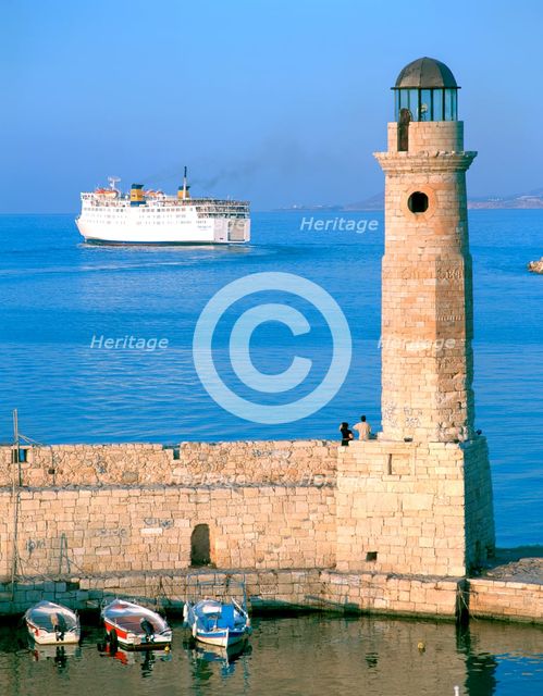 Venetian lighthouse and the ferry to Piraeus, Rethymnon, Crete, Greece.