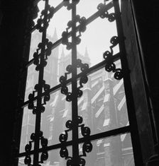 View through a wrought iron window grille towards the south facade of Westminster Abbey, 1947-57. Creator: John Gay