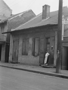 View from across street of a woman standing by a doorway in the French Quarter, New..., c1920-c1926. Creator: Arnold Genthe