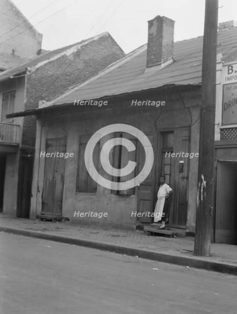 View from across street of a woman standing by a doorway in the French Quarter, New..., c1920-c1926. Creator: Arnold Genthe.
