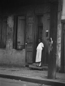 View from across street of a woman standing in a doorway in the French Quarter, New..., c1920-c1926. Creator: Arnold Genthe
