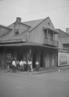 View from across street of a group of men on a street corner, New Orleans, between 1920 and 1926. Creator: Arnold Genthe