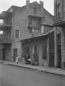 View from across street of a man and child sitting on steps and a woman walking down..., c1920-1926. Creator: Arnold Genthe