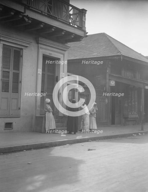 View from across street of four women talking, New Orleans, between 1920 and 1926. Creator: Arnold Genthe.
