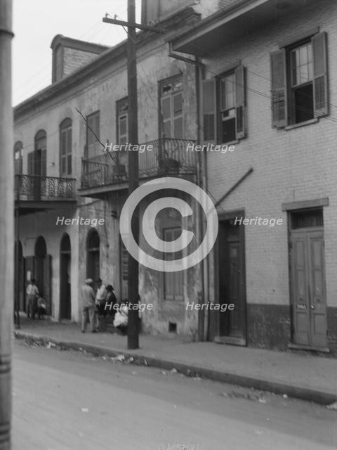 View from across street of four people talking in the French Quarter, New Orleans, c1920-1926. Creator: Arnold Genthe.