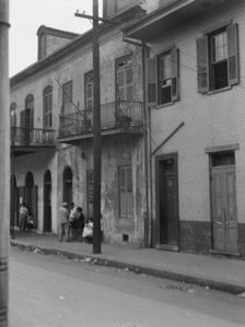 View from across street of four people talking in the French Quarter, New Orleans, c1920-1926. Creator: Arnold Genthe