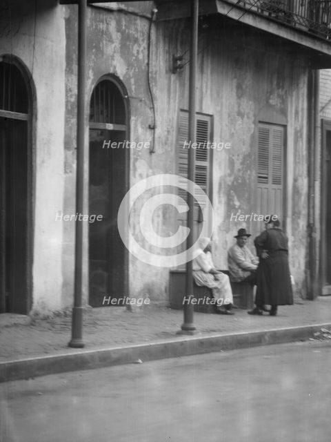View from across street of people talking, New Orleans, between 1920 and 1926. Creator: Arnold Genthe.