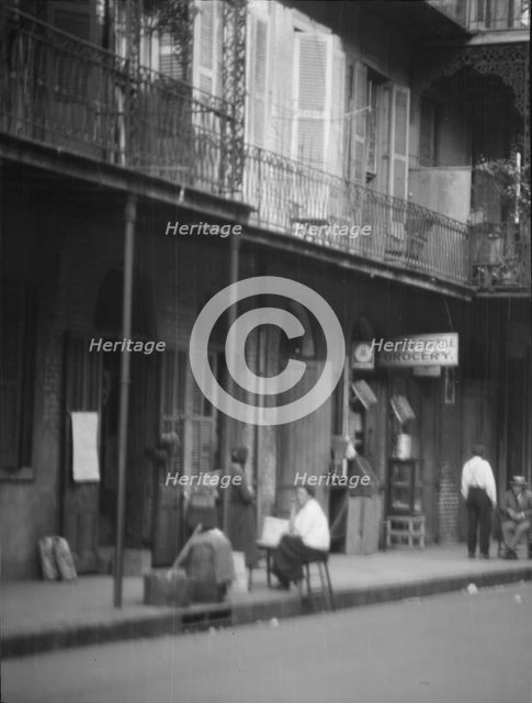 View from across street of people under a covered sidewalk, New Orleans, between 1920 and 1926. Creator: Arnold Genthe.