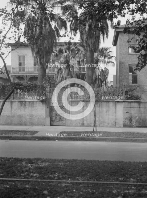 View from across street of two-story house behind wall, New Orleans, between 1920 and 1926. Creator: Arnold Genthe.
