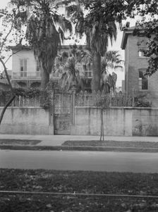 View from across street of two-story house behind wall, New Orleans, between 1920 and 1926. Creator: Arnold Genthe