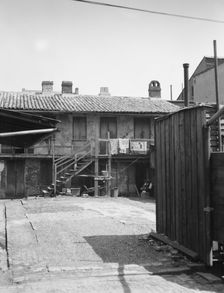 View of two-story dwellings with laundry hanging over balcony railing, New Orleans, c1920-1926. Creator: Arnold Genthe